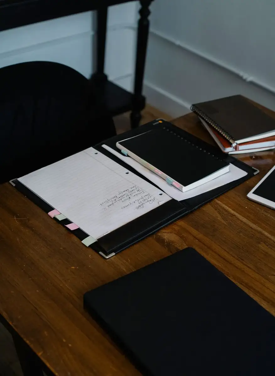 Notebooks and a tablet arranged on a wooden workspace